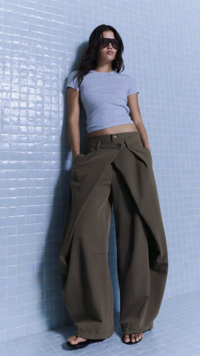 Modelka v modrém tričku a tmavých širokých kalhotách