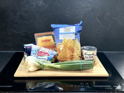 Tortilla chips, mozzarella, cheddar, jarní cibulka, rajčatový protlak a fazole v konzervě na dřevěném prkénku