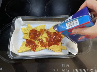 Nachos a rajčatový protlak na plechu vyloženém pečicím papírem