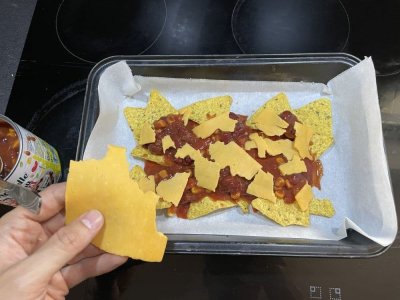 Nachos, rajčatový protlak, fazolová směs a sýr na plechu vyloženém pečicím papírem