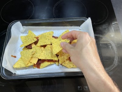 Nachos, rajčatový protlak, fazolová směs a sýr na plechu vyloženém pečicím papírem
