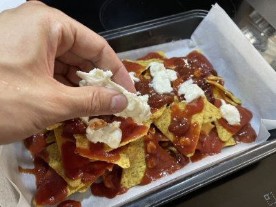 Nachos, rajčatový protlak, fazolová směs a sýr na plechu vyloženém pečicím papírem