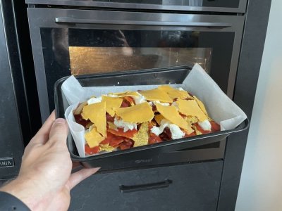 Nachos, rajčatový protlak, fazolová směs a sýr na plechu vyloženém pečicím papírem