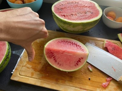 Muž dává palec dolů před rozkrojeným melounem