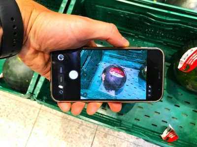 Muž fotí meloun v supermarketu přes mobilní telefon