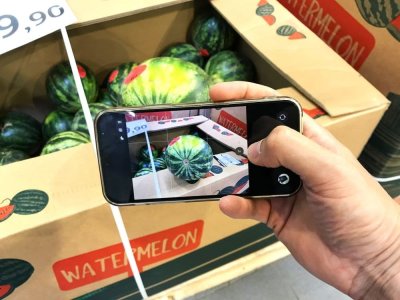 Muž fotí meloun v supermarketu přes mobilní telefon
