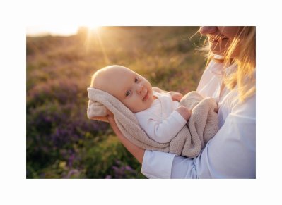 Žena s novorozencem v přírodě při západu slunce