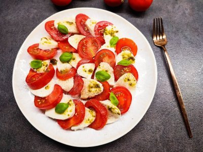 Salát Caprese s mozzarellou a bazalkou, servírovaný na bílém talíři