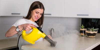 Žena čistí kuchyňskou linku pomocí parního čističe