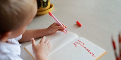 Dítě drží v levé ruce pero a píše