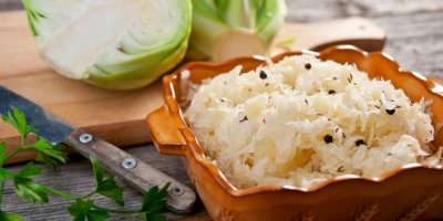 Kysané zelí v kameninové misce a za ním hlávka zelí ke krouhání