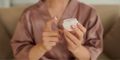 Žena si namáčí prst do dózy s krémem.