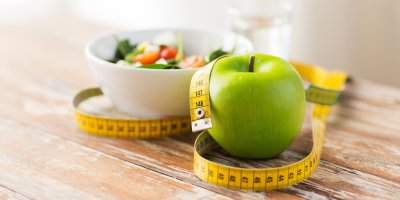 Krejčovský metr kolem jablka a misky se salátem