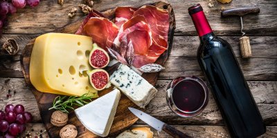 Láhev červeného vína a na prkénku delikatesy