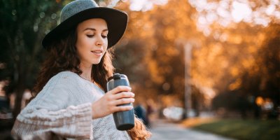 Žena ve svetru drží v ruce termohrnek