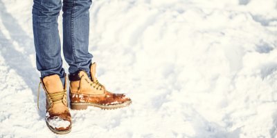 Muž stojí ve sněhu v zimních botách