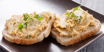 Dva plátky toastu namazané pomazánkou a ozdobené bylinkami