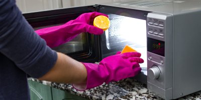 Člověk čistí mikrovlnku pomocí houbičky a citronové šťávy