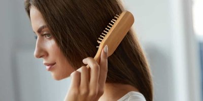 Žena si češe vlasy dřevěným hřebenem.