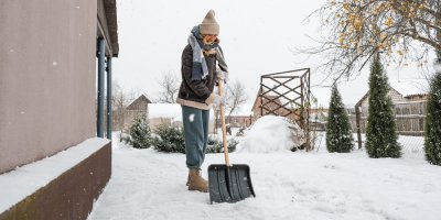 Žena uklízí sníh před domem