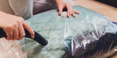 Žena vysává vzduch z vakuového pytle, ve kterém jsou zimní bundy