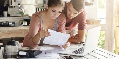 Mladý pár kontroluje své finance na notebooku a ve smlouvách