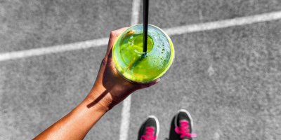 Žena drží zelené smoothie v plastovém kelímku