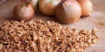 Sušená nakrájená cibulka a cibule v pozadí