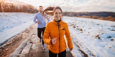 Žena a muž běžící zimní krajinou