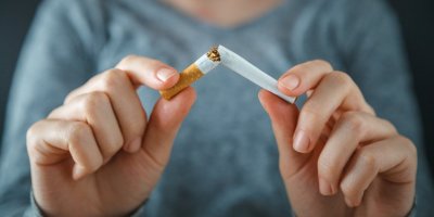 Žena drží v rukou zlomenou cigaretu.