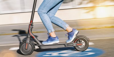 Žena jede na elektrokoloběžce po silnici.