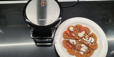 Vaflovač a vafle ve tvaru srdcí s jahodami, šlehačkou a čokoládou