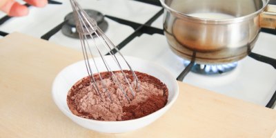 Žena míchá metličkou kakao v misce