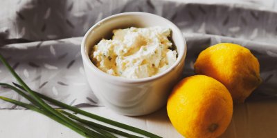 Česneková pomazánka v bílé misce, vedle dva citrony