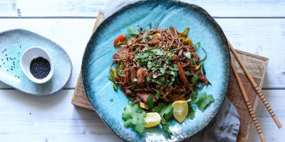 Pohled shora na modrý talíř se soba nudlemi s kuřecím masem