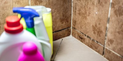 Plíseň v koupelně, v popředí čisticí prostředky