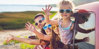 Děti ve slunečních brýlích mávající z auta