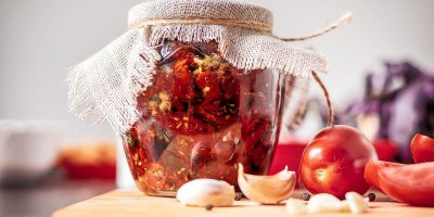 Sklenice se sušenými rajčaty, čerstvá rajčata, česnek