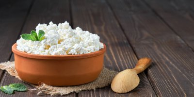 Cottage sýr ve velké keramické misce, dřevěná lžíce