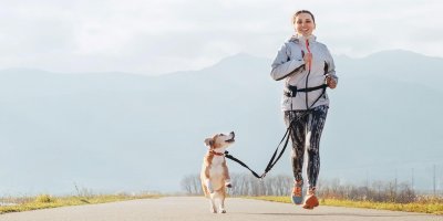 Žena běžící se psem na postroji po cestě