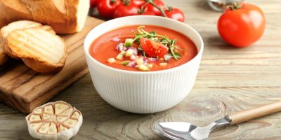 Miska s rajčatovou polévkou gazpacho, česnek, lžíce, bageta