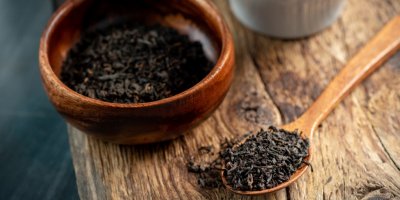 Dřevěná miska a vedle ní nasypaný černý čaj 