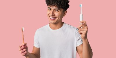 Muž drží obyčejný a elektrický kartáček