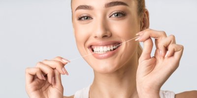Žena si čistí zuby nití
