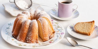 Pocukrovaná bábovka na talíři, kousek bábovky na talířku, šálek kávy