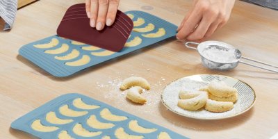 Žena plní formičky na pečení vanilkových rohlíčků