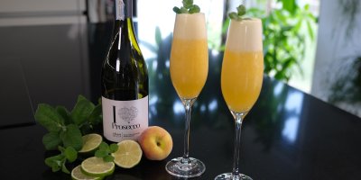 Lahev prosecca a dvě sklenice s nápojem na stole