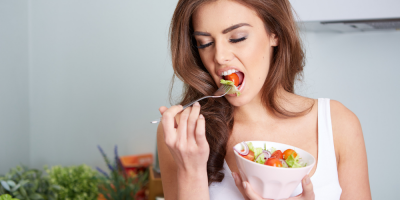 Žena jí zeleninový salát a drží misku se salátem