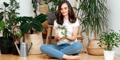 Žena sedí mezi pokojovými rostlinami