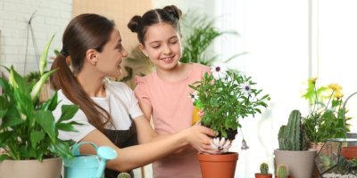 Žena pečuje s dcerou o pokojovou rostlinu rozprašovačem